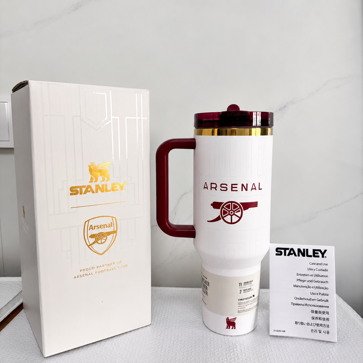 Stanley 40oz insulated tumbler featuring Arsenal FC-inspired design with matching collector gift box, white body, and red ergonomic handle