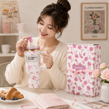 Woman holding a floral-patterned Stanley water bottle in a cozy indoor setting.