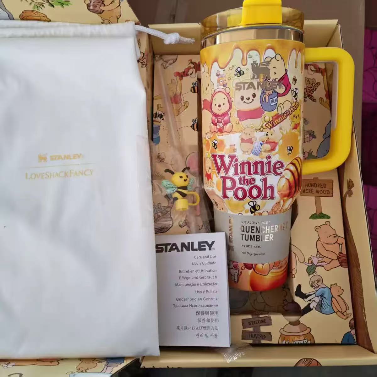 Stanley 40oz insulated tumbler featuring Winnie the Pooh and friends artwork, honey-themed design, yellow handle, includes themed accessories