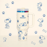 Stanley 40oz insulated tumbler featuring Snoopy illustrations, blue paw prints and bone icons, white body with white ergonomic handle